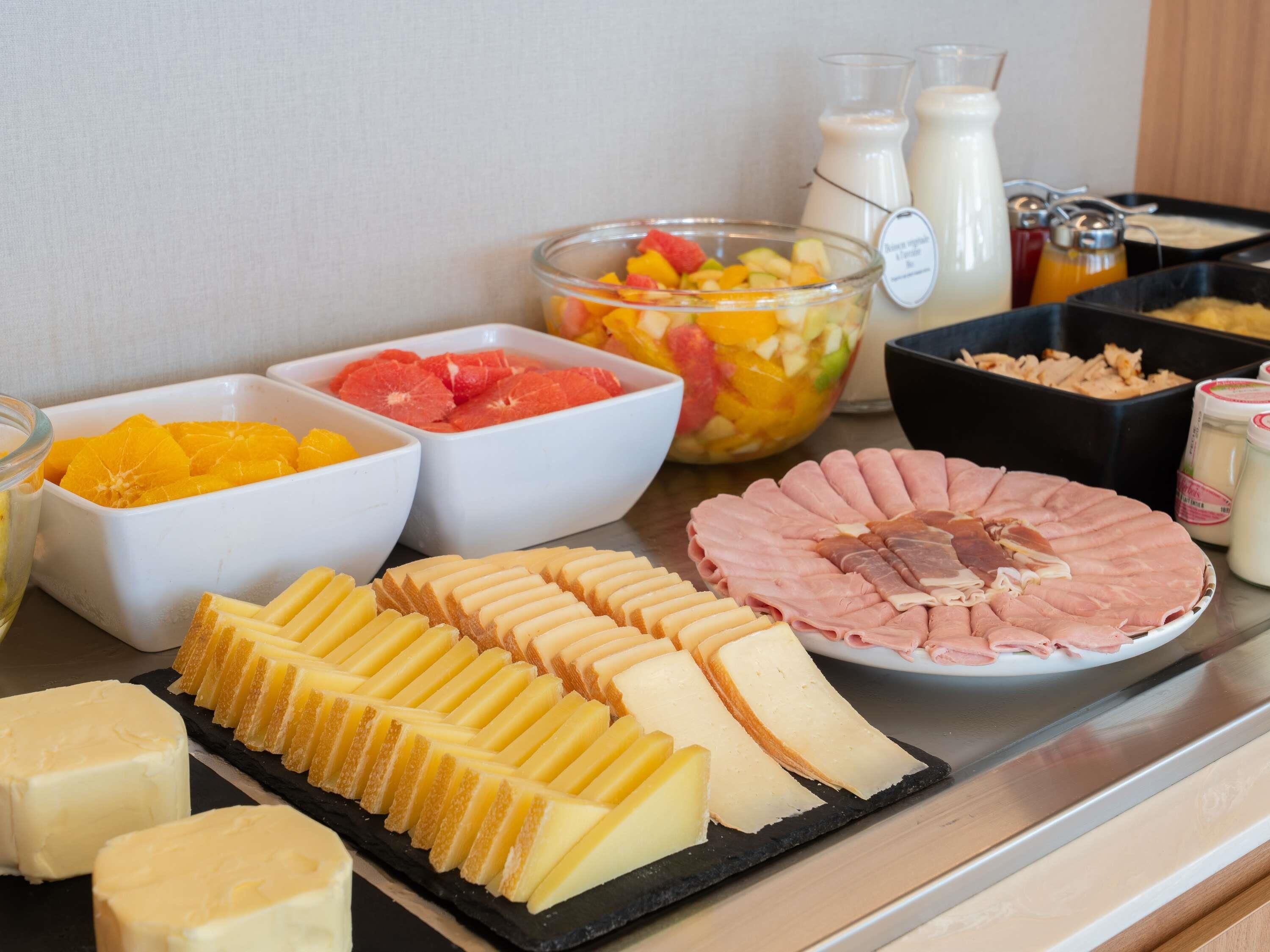 Un bufé con diversas opciones de comida, incluyendo frutas, quesos y carnes.
