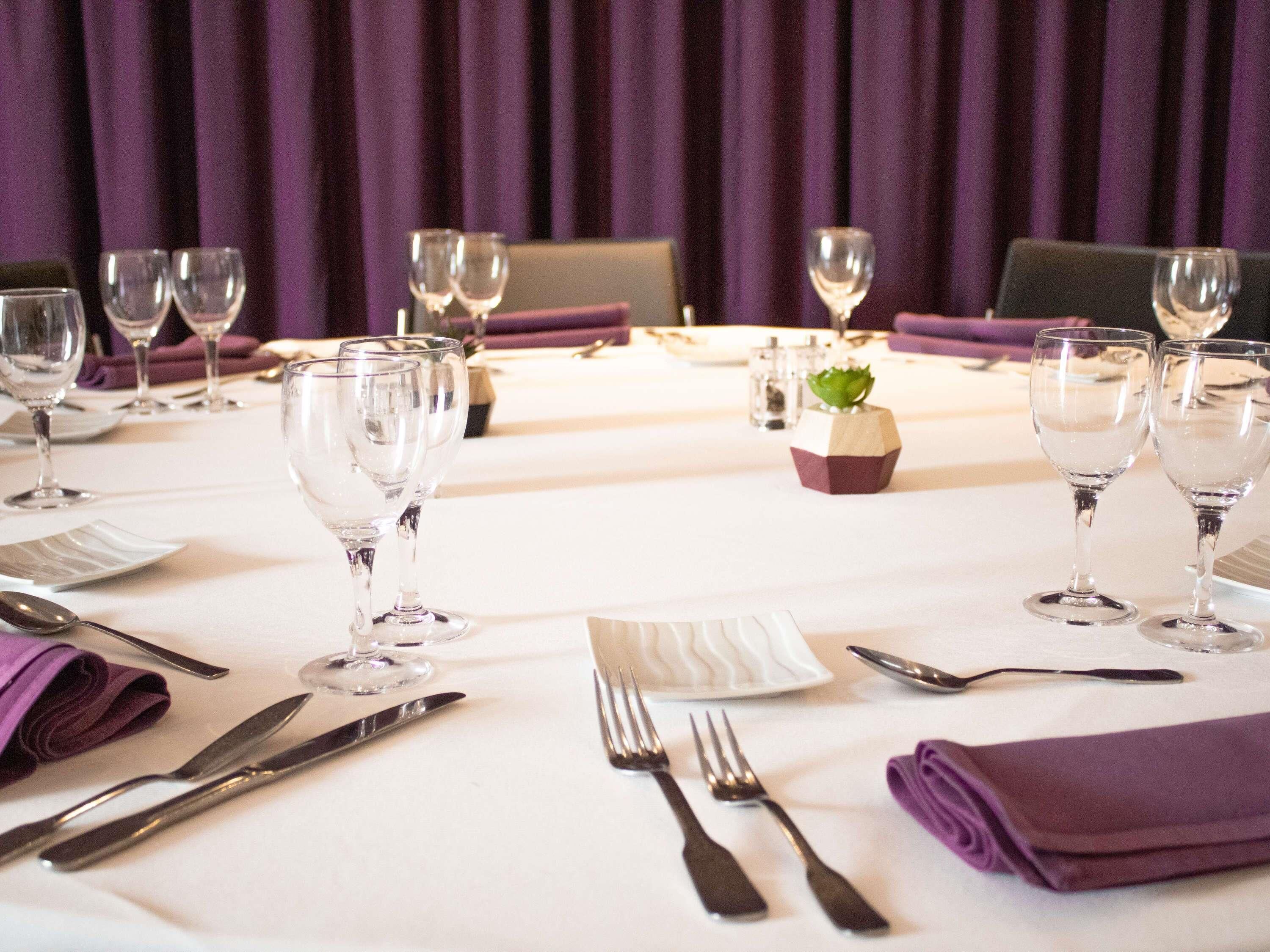 A table set for dining with wine glasses, cutlery, and a small decorative centerpiece.