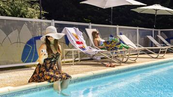 Una piscina al aire libre de temporada, sombrillas