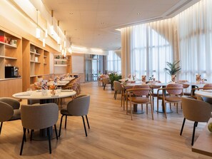 A modern dining area with round tables, chairs, and pendant lighting.