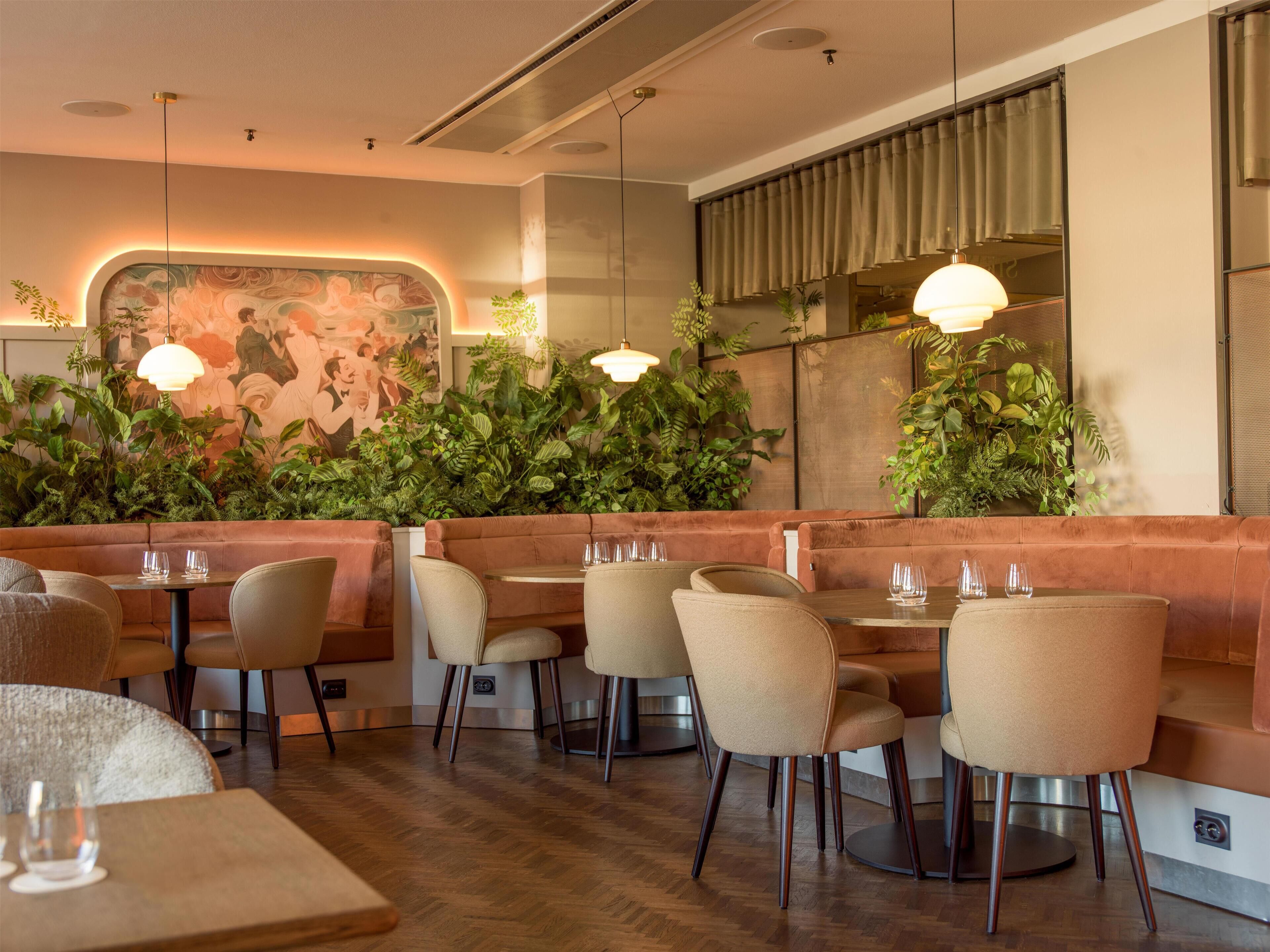 Un interior de restaurante con suelo de madera, asientos tipo banca acolchados y mesas.