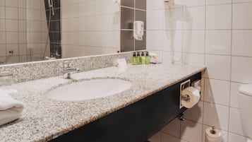 A modern bathroom with two sinks, a large mirror, and a shower.