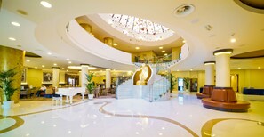 A spacious lobby with a central staircase, seating areas, and a piano. - Don Giovanni Hotel Prague - Great Hotels of the World (Prague)