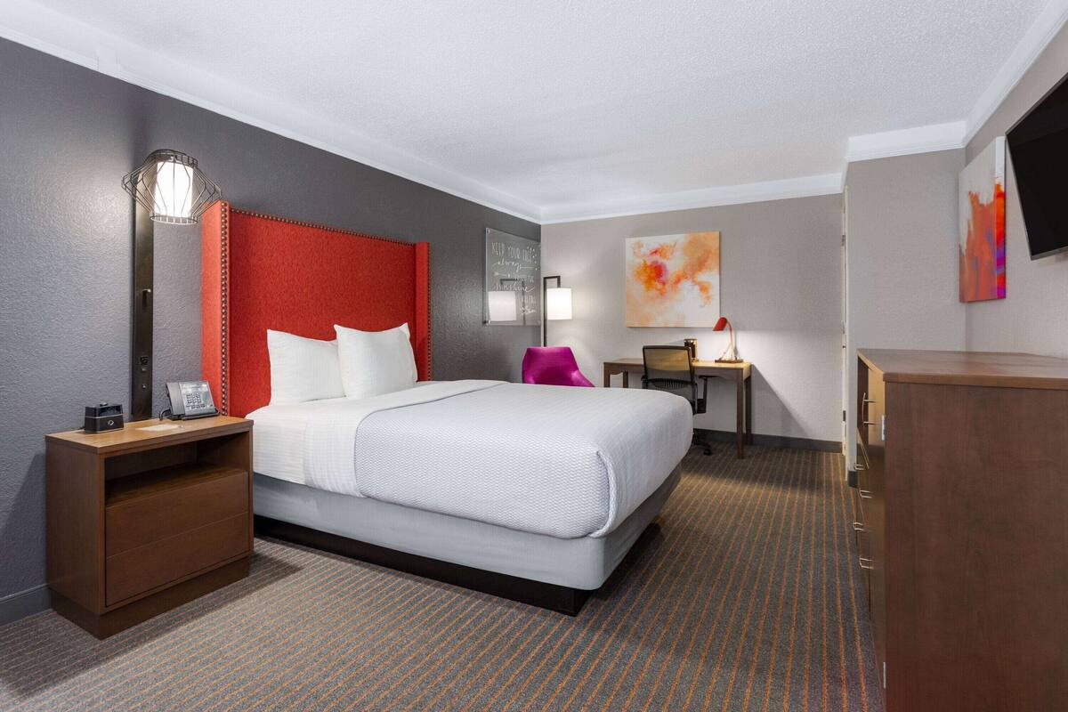 Une chambre d’hôtel avec un grand lit, un bureau, une table de chevet, une lampe et un téléviseur.