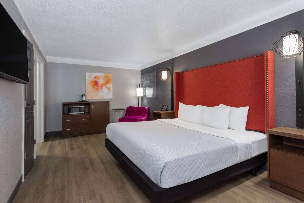 Une chambre d’hôtel avec un grand lit, un bureau, une chaise, une télévision et un four à micro-ondes.