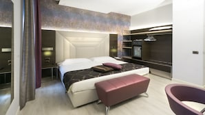 Una habitación de hotel moderna con una cama grande, una zona de estar y un televisor.