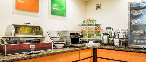 A breakfast bar with a sizzle station, coffee makers, and a refrigerated display.