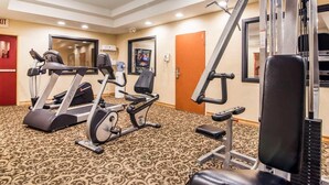 Une salle de sport d’hôtel équipée de machines de cardio, d’appareils de musculation et d’un miroir.
