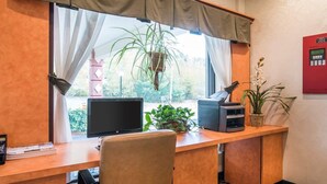 Une chambre d’hôtel équipée d’un bureau, d’une chaise, d’une télévision, d’une imprimante et d’une fenêtre avec des rideaux.