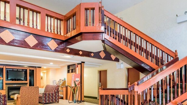 Un vaste espace de vie agrémenté d’un escalier en bois, d’une cheminée et de sièges confortables.