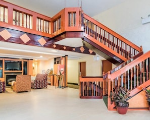 A spacious living area with a wooden staircase, a fireplace, and comfortable seating.