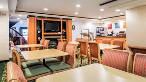 Un espace de restauration dans l’hôtel, avec des tables et des chaises, une cheminée, un téléviseur et une machine à café.