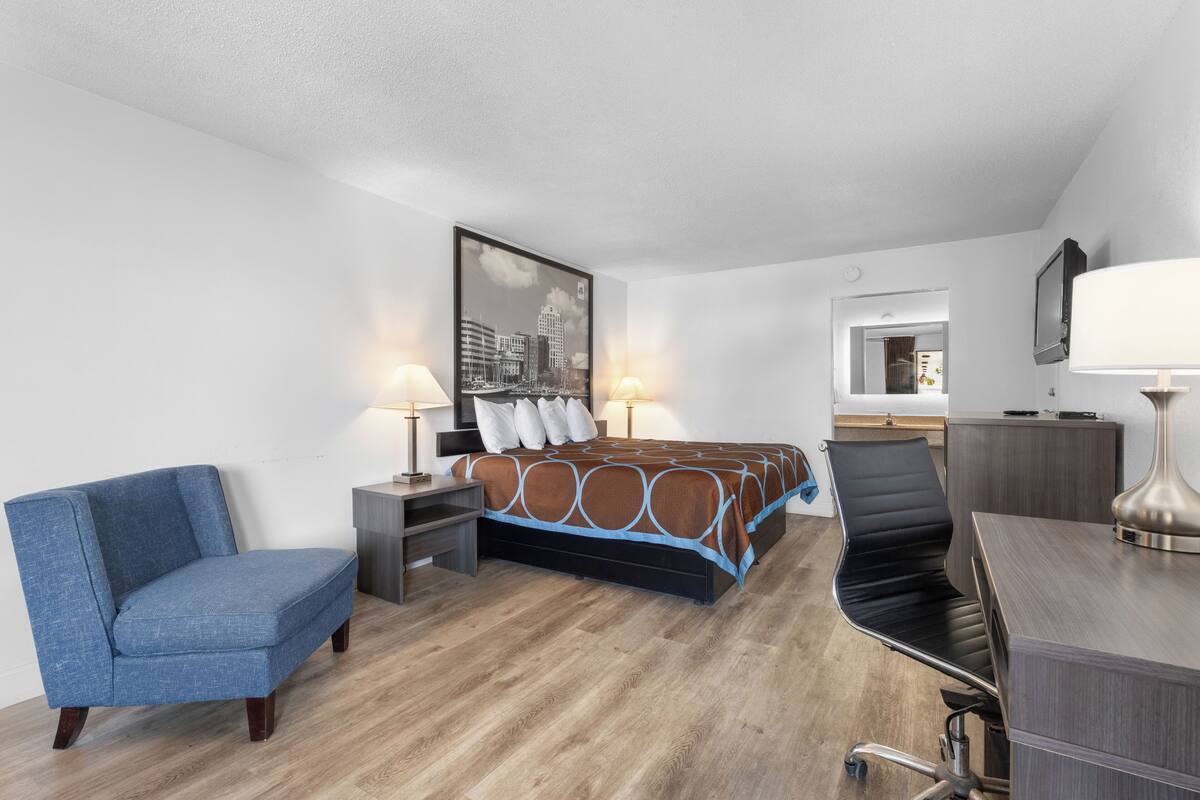 Une chambre d’hôtel avec un lit, un bureau, une chaise et un téléviseur.