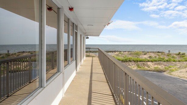 Ein überdachter Balkon mit Blick auf Strand und Meer.