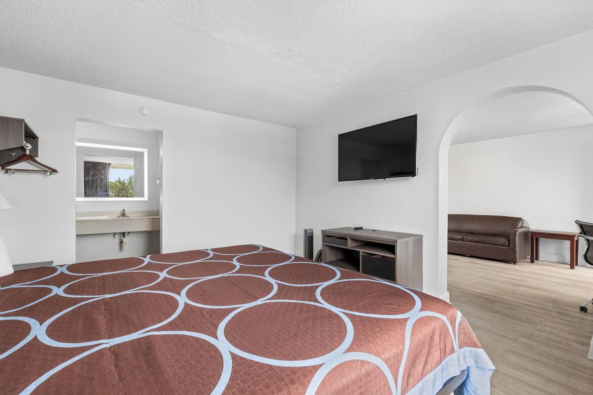 Une chambre d’hôtel avec un grand lit, un téléviseur à écran plat fixé au mur, un canapé et un bureau.