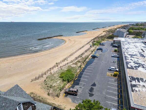 Un aparcamiento junto a la playa con coches y una playa de arena.