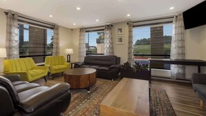 Una sala de estar moderna con un sofá, sillas, una mesa de centro y un televisor.