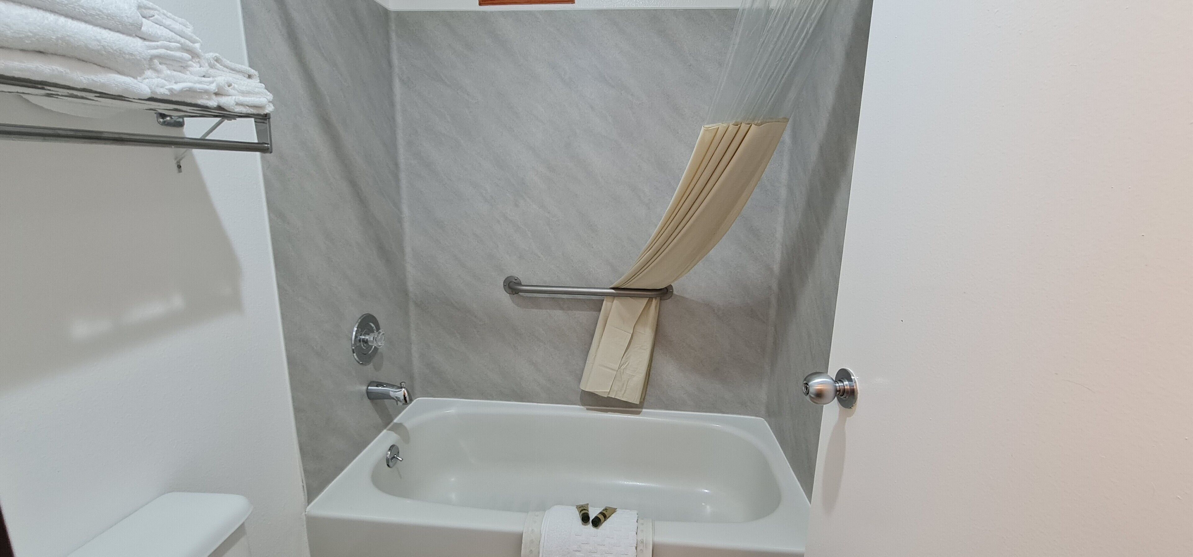 Ein Badezimmer mit einer Badewanne, einem Handtuchhalter mit gefalteten Handtüchern und einer Toilette.