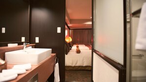 A hotel room with a large mirror, a white sink, a wooden vanity, and a bed with a red headboard. - Rose Hotel Yokohama (Yokohama)