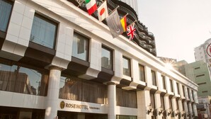 A hotel with a modern facade, multiple flags, and a prominent Rose Hotel sign.