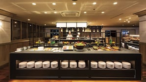 A buffet area with a variety of food items, plates, and serving utensils.