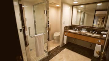 A modern bathroom with a glass-enclosed shower, two sinks, a large mirror, and a toilet.