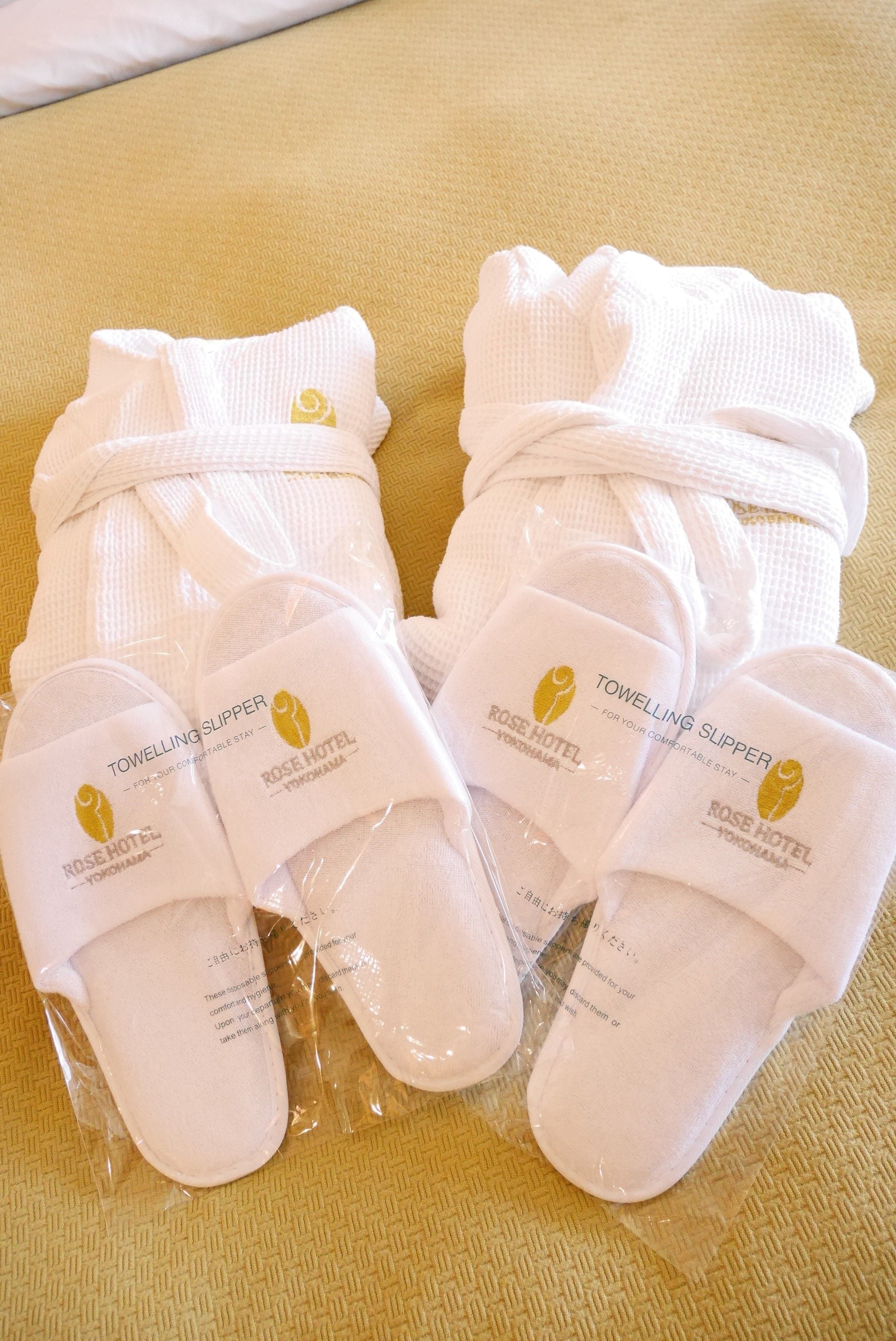 A pair of white slippers with a logo and text indicating they are from Rose Hotel.