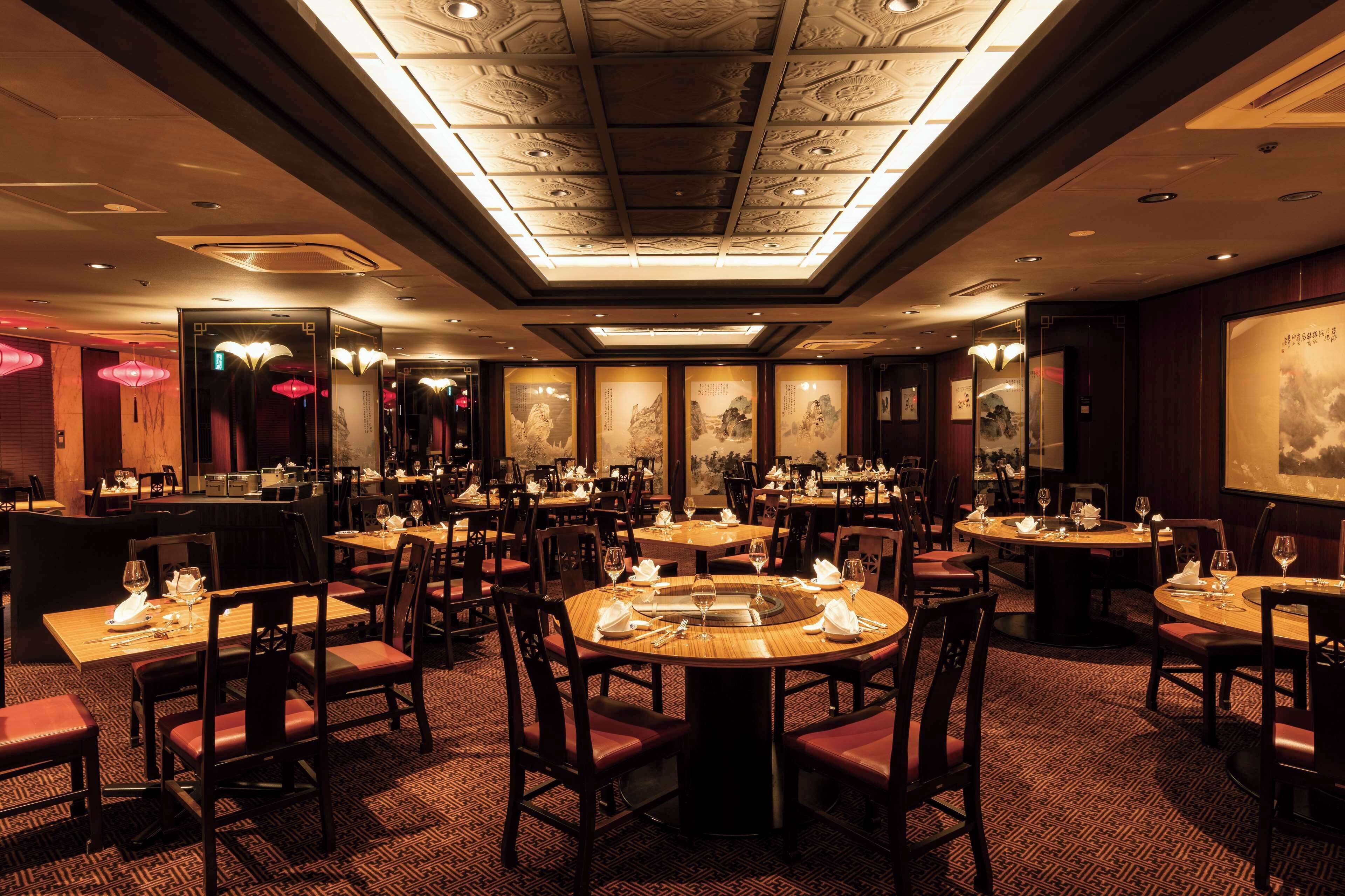A restaurant with round tables, chairs, and a patterned carpet.