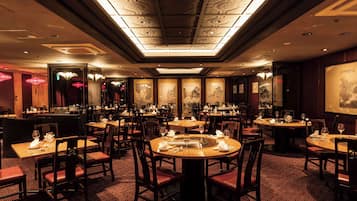 A restaurant with round tables, chairs, and a patterned carpet.