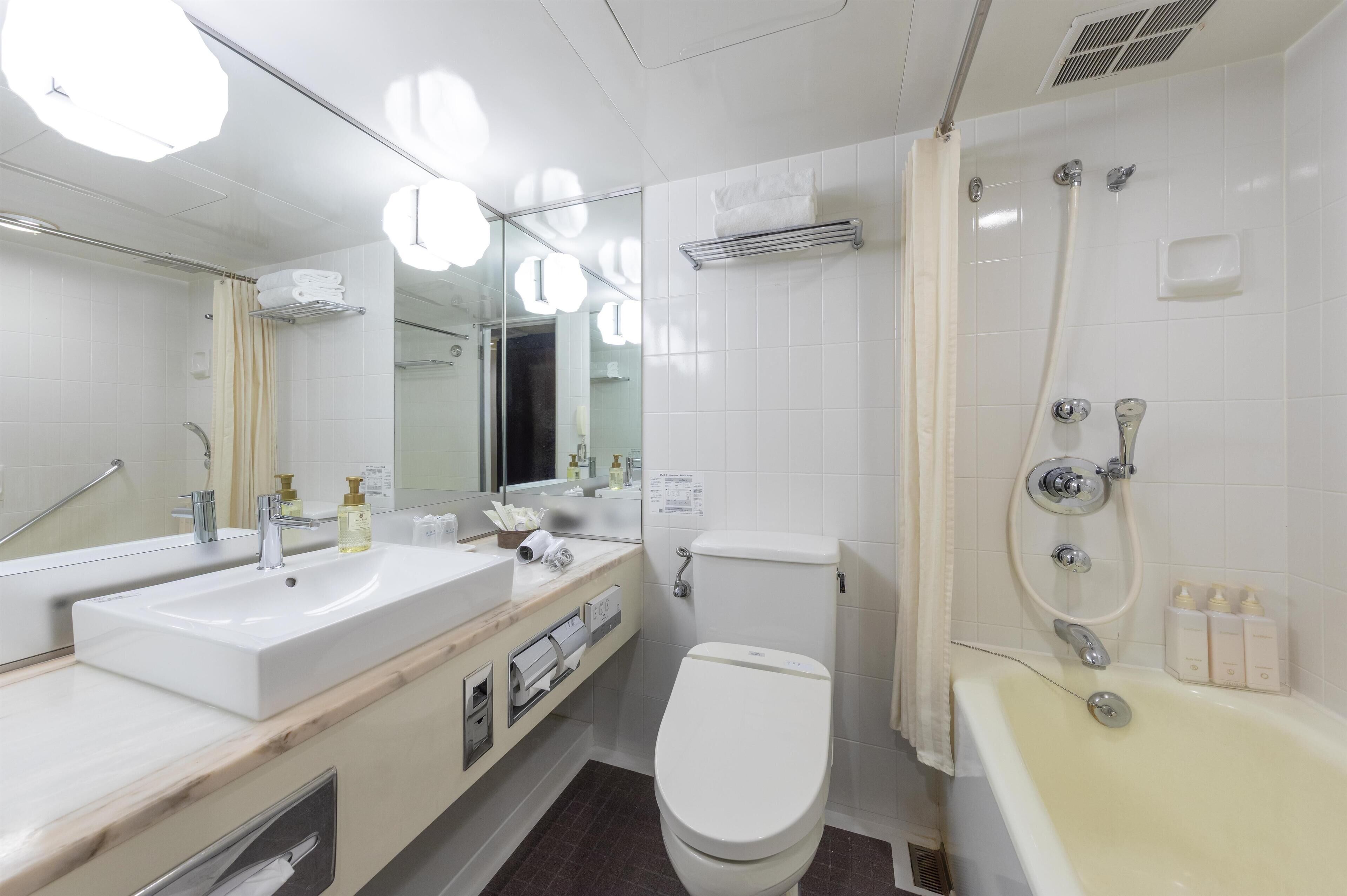 A modern bathroom with a sink, toilet, and bathtub.