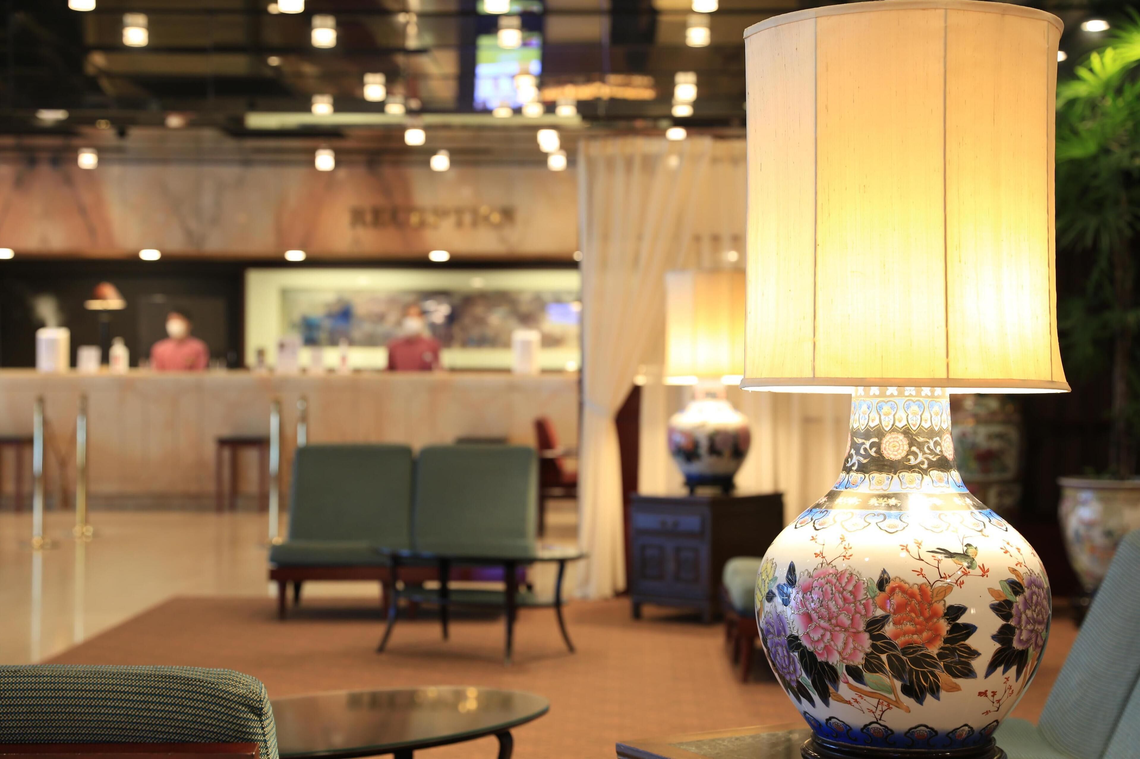 A lobby with a reception desk, seating area, and a decorative lamp.