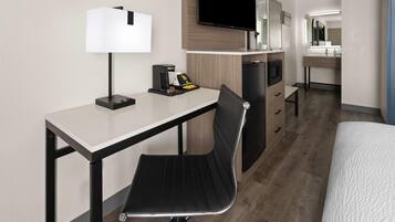 Una habitación de hotel con escritorio, silla, televisor y cama.