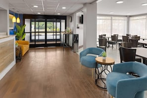 Un espace d’accueil moderne avec un plancher en bois, un comptoir d’accueil et un coin salon doté de chaises bleues.