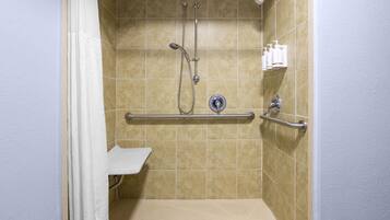 A shower with a grab bar, a handheld showerhead, and a handheld faucet.
