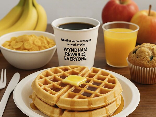 A breakfast setting with waffles, a muffin, a bowl of cereal, a cup of coffee, and a glass of orange juice. - Baymont by Wyndham Fayetteville NC (Fayetteville)