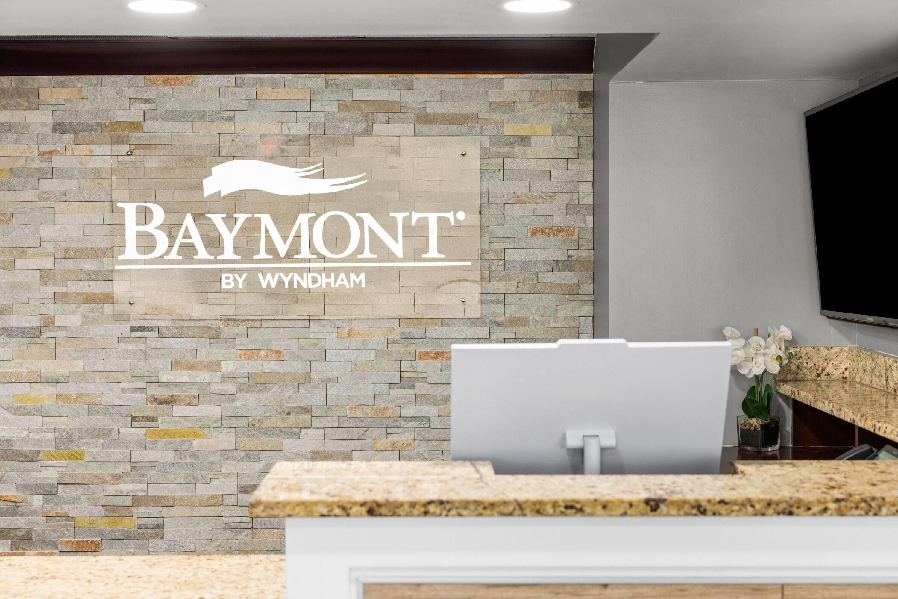A reception area with a stone wall and a Baymont by Wyndham sign.