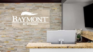 A reception area with a stone wall and a Baymont by Wyndham sign.