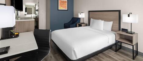 Une chambre d’hôtel comprenant un lit, un bureau, une chaise, une télévision et une salle de bain.