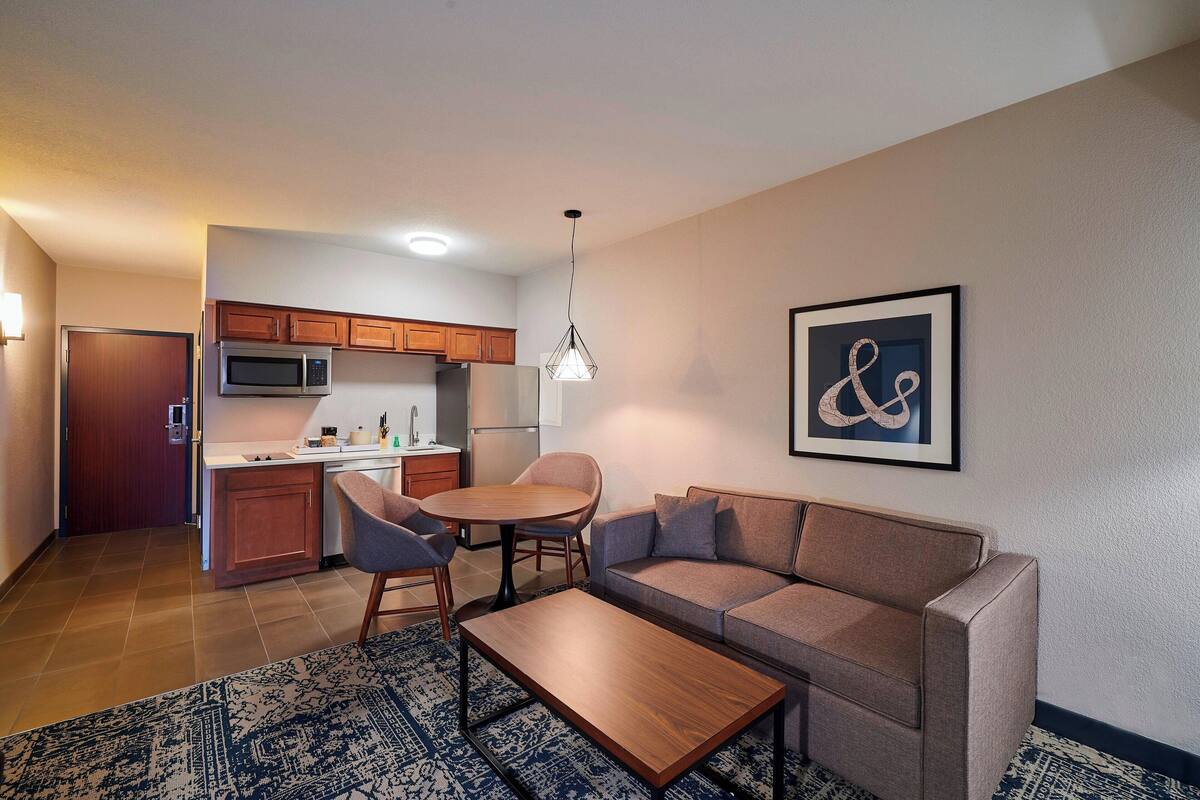 A compact living space with a kitchenette, a sofa, a coffee table, and a dining area.