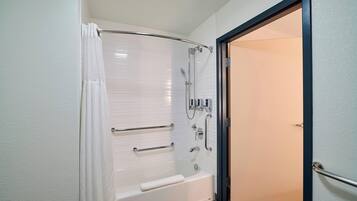 A modern bathroom with a walk-in shower, grab bars, and a towel rack.