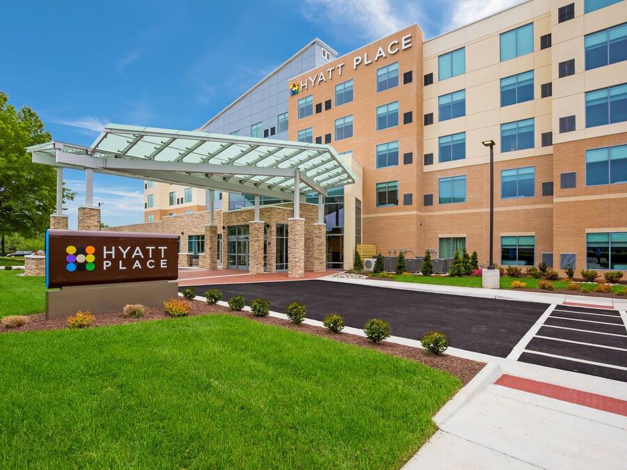 Ein Hyatt Place Hotel mit überdachter Eingangspartie, einem Parkplatz und einem gepflegten Rasen.
