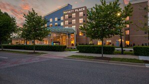 Un hotel Hyatt Place moderno con entrada cubierta, jardines bien cuidados y un cielo despejado al anochecer.