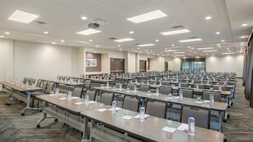 A large conference room with rows of tables, chairs, and water bottles.