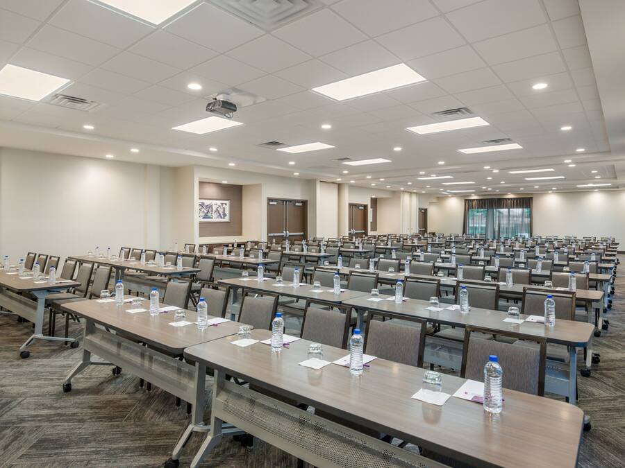 A large conference room with rows of tables, chairs, and water bottles.