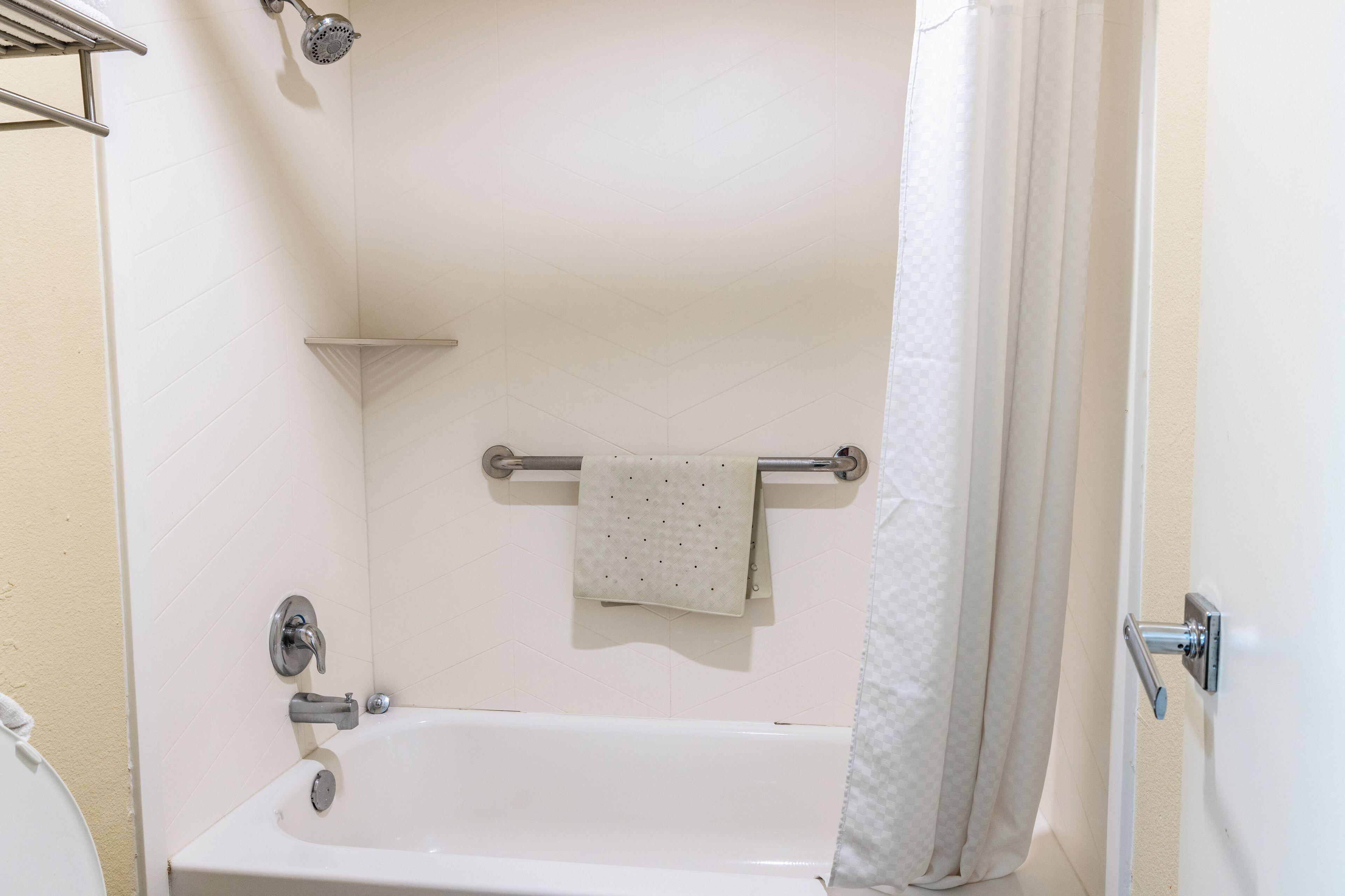 A bathroom with a bathtub, a showerhead, a towel rack, and a toilet.