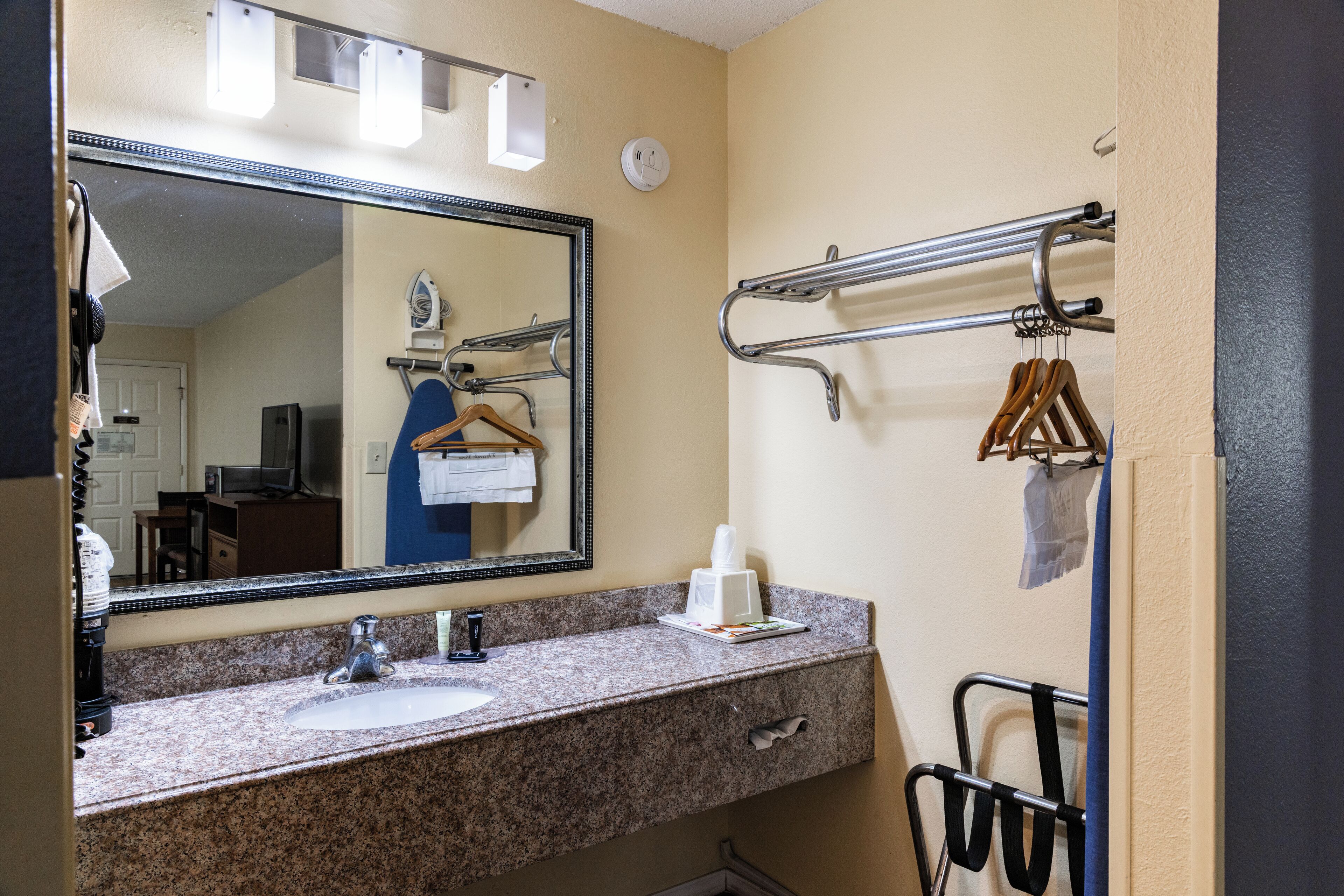 Une salle de bain équipée d’un lavabo, d’un miroir, d’un porte-serviettes et d’un sèche-mains.
