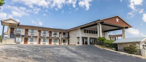 A multi-story hotel with a central atrium, outdoor parking, and a clear sky.