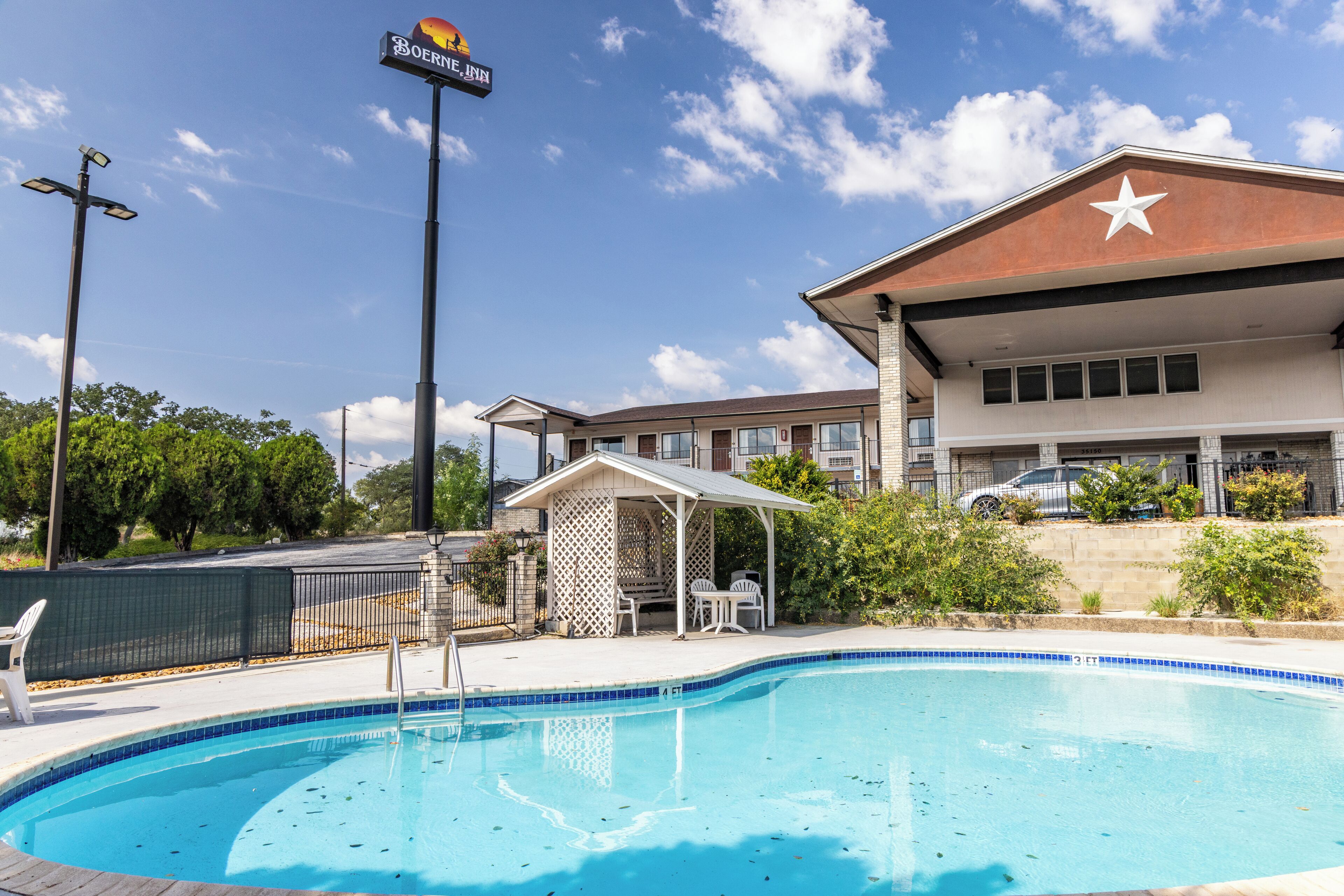 A hotel with a swimming pool, outdoor seating, and a star on the building.