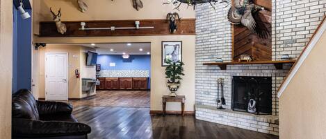 A spacious living room with a fireplace, a chandelier, and mounted animal heads on the wall.