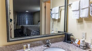 A hotel bathroom with a large mirror, a sink, and a hairdryer.